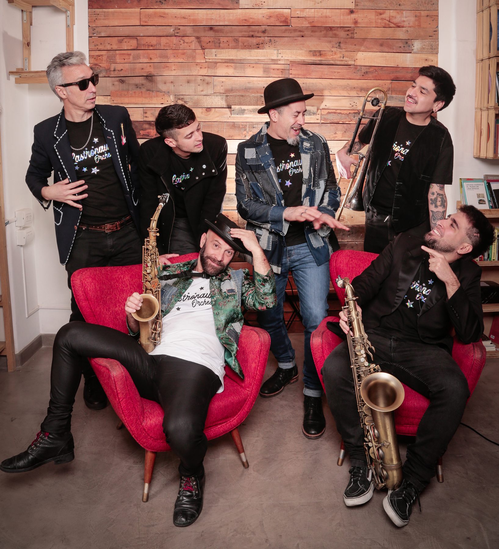 La banda riéndose entre sillones rojos, con saxos y trombón